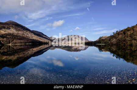 Guardando verso il lato nord della Buttermere con Melbreak perfettamente riflessa su un croccante di mattina di primavera Foto Stock