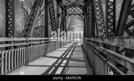 Vista di un vecchio ponte ferroviario convertito in un parco trail; Missouri, Midwest; nero e bianco; ombre lunghe Foto Stock
