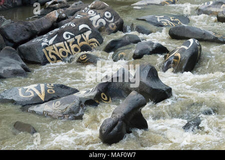 Rocce dipinte con parole di preghiera nel fiume, Tagong, western Sichuan, Cina Foto Stock