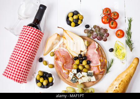 Antipasto Italiano antipasto, prosciutto, olive, formaggio, pane, uva pera e vino bianco su uno sfondo di legno Foto Stock
