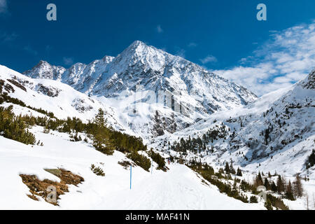 Vista del 3500m alto Schrankogel nell'Oetztal, Austria con paesaggi innevati e cielo blu, una strada innevata in primo piano. Foto Stock