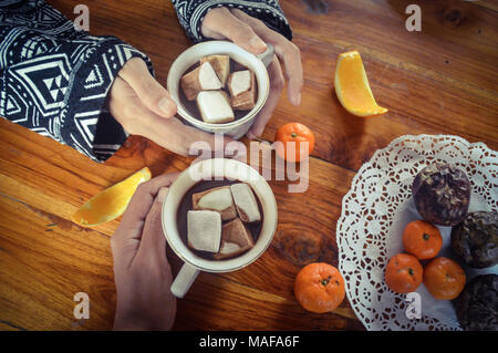 Condivisione di una tazza di cioccolata calda a bere con marshmallows in una fredda mattina presto Foto Stock