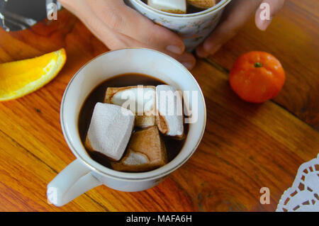 Condivisione di una tazza di cioccolata calda a bere con marshmallows in una fredda mattina presto Foto Stock