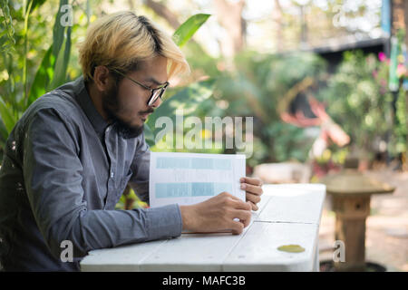 Giovani hipster barba uomo la lettura di libri nel giardino di casa con la natura. Il concetto di istruzione. Foto Stock