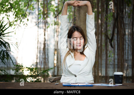 Giovane imprenditrice stretching se stessa e sbadigli al lavoro, pronto per il lavoro. Foto Stock