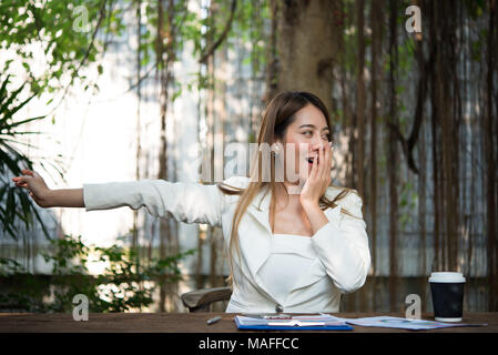 Giovane imprenditrice stretching se stessa e sbadigli al lavoro, pronto per il lavoro. Foto Stock