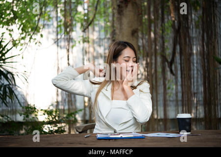 Giovane imprenditrice stretching se stessa e sbadigli al lavoro, pronto per il lavoro. Foto Stock