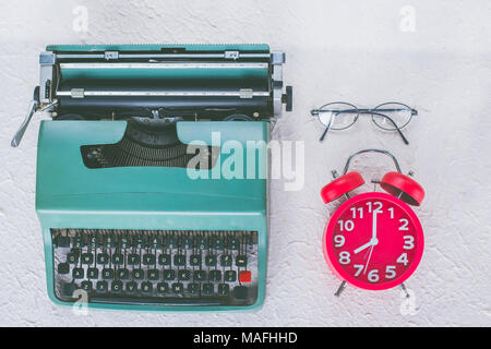 Vista superiore della macchina da scrivere vintage con sveglia rossa e occhiali su sfondo bianco Foto Stock