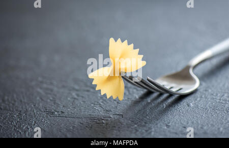 Farfalle di pasta sulla forcella close up, il fuoco selettivo, copia dello spazio. Foto Stock