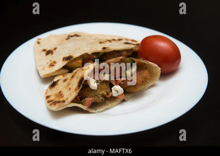 Pane Pita riempito con falafel e insalata isolato su nero Foto Stock