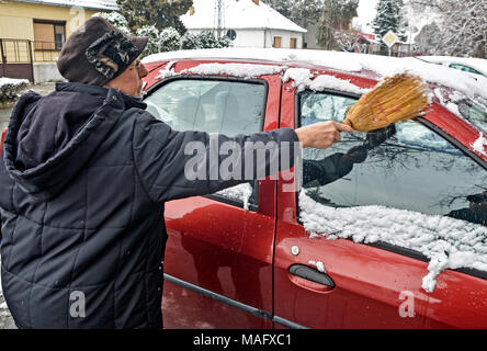 Driver donna pulisce la neve dalla macchina a mano e il pennello. Foto Stock