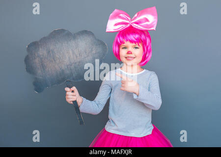 Bambina pointong dito alla tavola nera. Studio shot, isolata su uno sfondo grigio Foto Stock