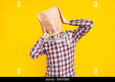 Uomo con pacchetto sulla testa,tenendo la sua testa. Il giorno dello sciocco di emozioni e sentimenti. Piscina shot, sfondo giallo Foto Stock