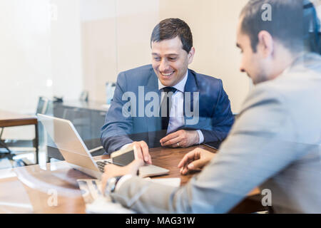 Due giovani imprenditori utilizzando computer portatile alla riunione di affari. Foto Stock