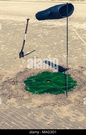 Una pala di un foro del golf e un anemometro sulla spiaggia Foto Stock