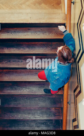 Una donna si erge su per le scale guardando verso l'alto con una matita nella mano destra Foto Stock