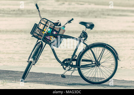 Una vecchia bicicletta olandese con un cesto pieno di roba parcheggiato sulla spiaggia Foto Stock