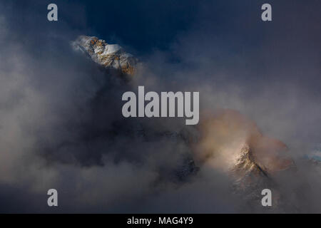 Un momento molto bello come la luce del pomeriggio tocca i picchi di una catena di montagne avvolte in rapido movimento di cloud, campo base Everest, Nepal Foto Stock