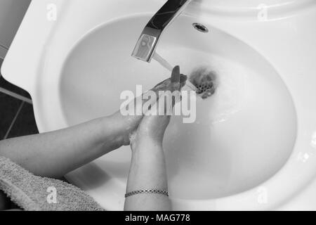 Foto in bianco e nero di lavare le mani delle donne nel lavandino. Foto Stock