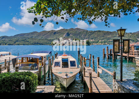 Barche ancorate lungo il piccolo molo in legno sul lago d'Orta - famoso e molto popolare località turistica e meta di viaggio nel Nord Italia. Foto Stock