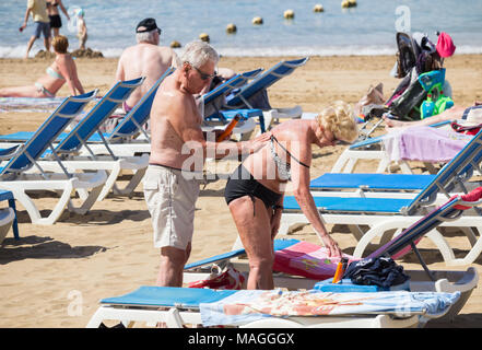 Coppia di anziani applicando lozione solare/crema sulla spiaggia in Spagna Foto Stock