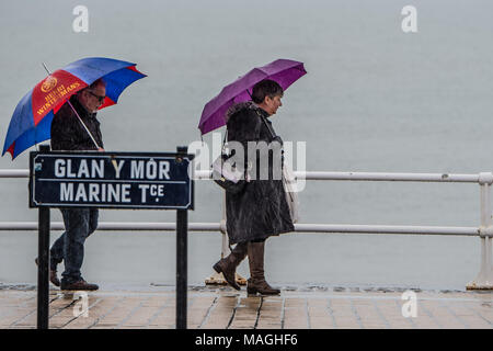 Aberystwyth Wales UK, lunedì 2 aprile 2018 UK Bank Holiday Meteo: persone riparo sotto i loro ombrelli come essi a piedi lungo la passeggiata sotto la pioggia battente su una misera e bagnato il lunedì di Pasqua bank holiday in Aberystwyth sulla West Wales coast foto © Keith Morris / Alamy Live News Foto Stock