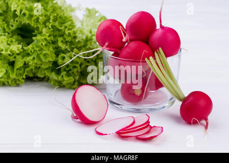 Ravanelli e lattuga su sfondo bianco. Intero e a fettine i ravanelli close up. Fresca insalata verde. Mangiare meglio e sentirsi meglio. Foto Stock