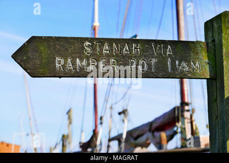 In legno antico segno di direzione di puntamento Stanah tramite elemento di tenuta Pot con barca a montanti in background,Thornton,Lancashire, Regno Unito Foto Stock