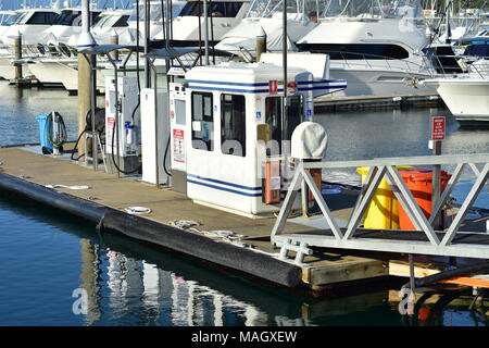 Pontile galleggiante con terminali di rifornimento in marina con barche di potenza in background. Foto Stock