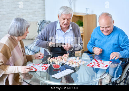 Senior amici Riproduzione Lotto in casa di riposo Foto Stock