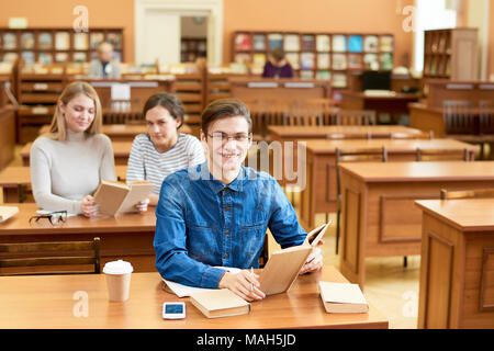 Emozionato diligente gli studenti in biblioteca Foto Stock