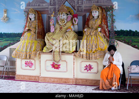 Un indù adoratore di pregare e meditare nei pressi di statue di divinità e Dee il Tulsi Mandir Tempio di South Richmond Hill, Queens, a New York. Foto Stock