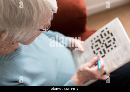 Senior donna facendo cruciverba in casa Foto Stock