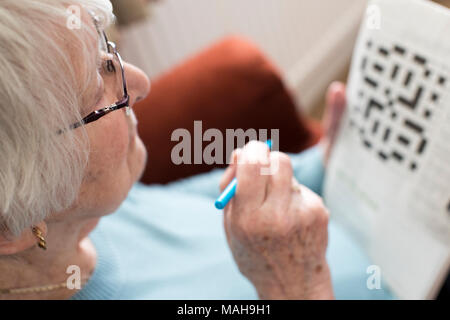 Senior donna facendo cruciverba in casa Foto Stock