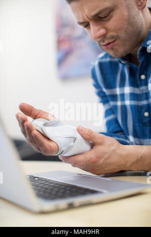 Uomo d affari con computer portatile che soffrono di lesioni da sforzo ripetitivo (RSI) Foto Stock