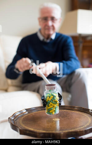 Senior uomo utilizzando raggiungendo il braccio per ritirare il farmaco a casa Foto Stock