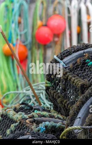 La pesca paraphernalia galleggianti di funi e reti appendere fuori ad asciugare con astice e granchio pentole sul lato del porto in un cornish villaggio di pescatori, Cornwall. Foto Stock