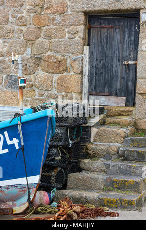 Un vecchio edificio costiere o fishermans capanna a sennen cove sulla west cornish coast con reti da pesca e una barca tradizionale su una sorta di scivolo in Cornovaglia. Foto Stock