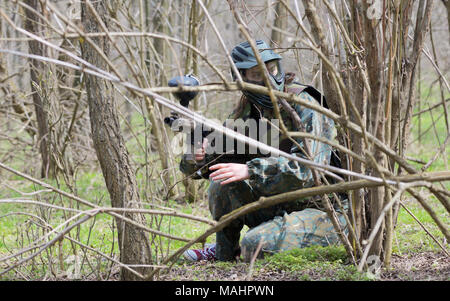 Il paintball player sotto attacco nella foresta Foto Stock