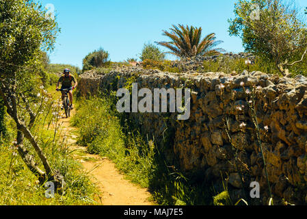 Mountain Biker vicino a Punta Prima sul Cami de Cavalls sentiero costiero lungo la costa di Minorca nelle Isole Baleari, Spagna Foto Stock