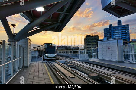 KAOHSIUNG, Taiwan -- Marzo 2, 2018: un treno di il nuovo sistema di ferrovia leggera di tira nell'amore stazione molo al tramonto del tempo. Foto Stock