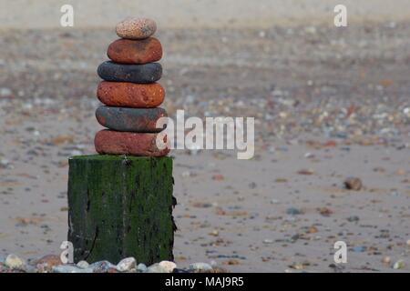 Pila di mare equilibrata indossato casa Mattoni su un Groyne Post. Spiaggia di Aberdeen, Scozia, Regno Unito. Foto Stock