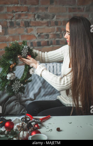 Perfetto giovane donna rendendo le decorazioni di Natale a casa Foto Stock