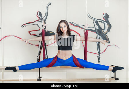 Sedetevi sui gruppi. Ragazza pratica anti-gravità salto di yoga. La donna non esercizio in palestra sull amaca per aria battenti yoga. attività sportiva in palestra o studio Foto Stock