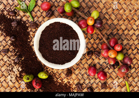 Caffè Fair trade background. Cofffea frutta, foglie, chicchi di caffè tostati dal di sopra su sfondo di legno. Foto Stock