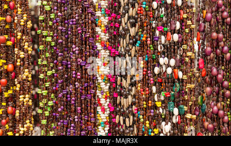 Stringhe di perline colorate in un mercato locale come una configurazione di sfondo Foto Stock