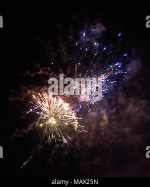 Luminose colorate di rosso e di blu fuochi d'artificio e fumo nel cielo notturno di close-up di sfondo verticale Foto Stock