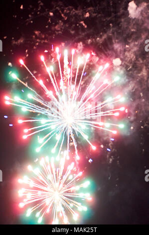 Luminose colorate di rosso e verde e fuochi d'artificio di fumo nel cielo notturno di close-up blured verticale sullo sfondo Foto Stock