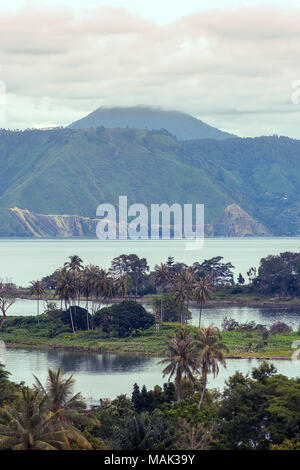 Mt Sinabung con il suo picco tra le nuvole visto dall isola di Samosir sul Lago Toba, Sumarta, Indonesia. Foto Stock