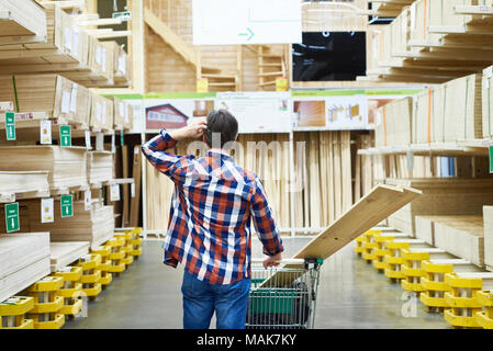 Uomo sceglie e acquista il legno compensato e pannelli in un supermercato di costruzione Foto Stock